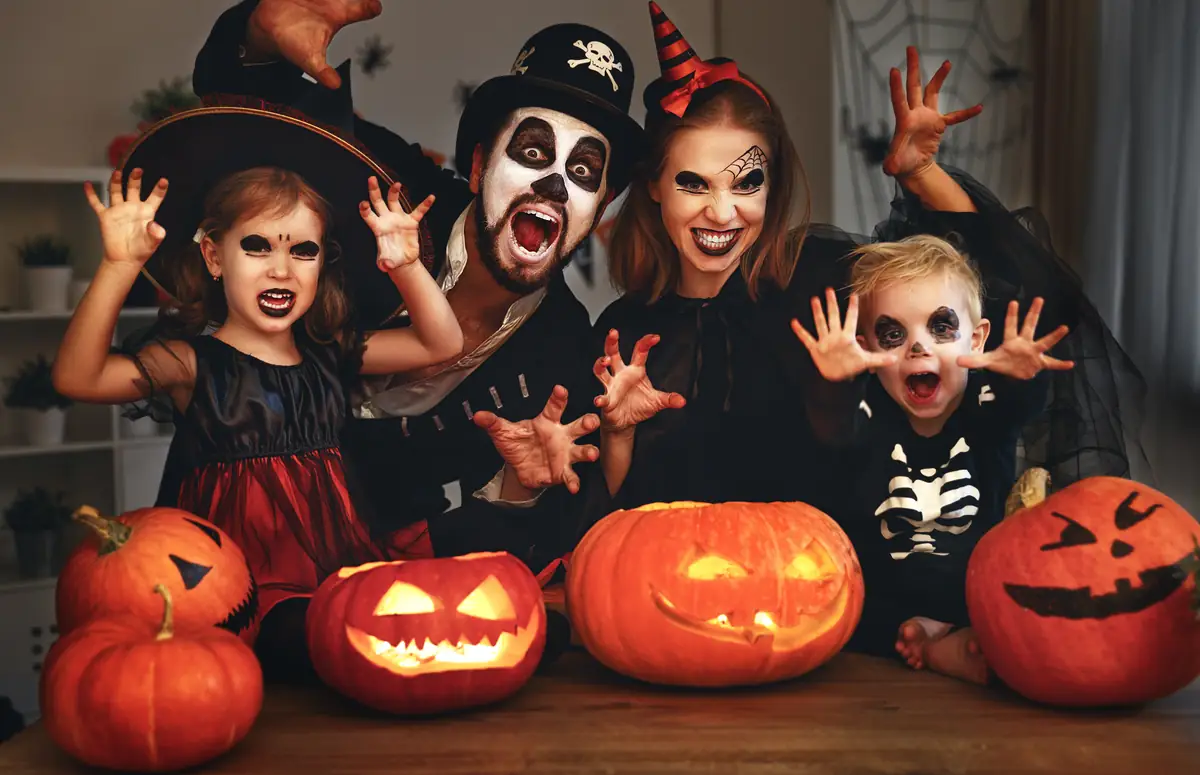 Familie in Halloween-Kostümen mit geschnitzten Kürbissen